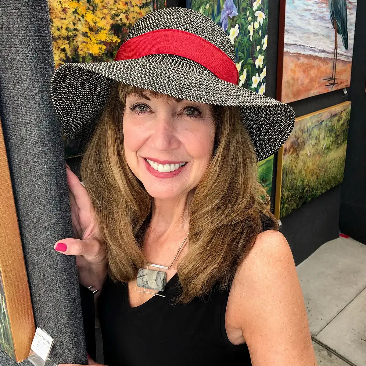 Artist headshot of Wisconsin acrylic painter Karen Watson-Newlin standing beside her impressionistic landscape and floral paintings.