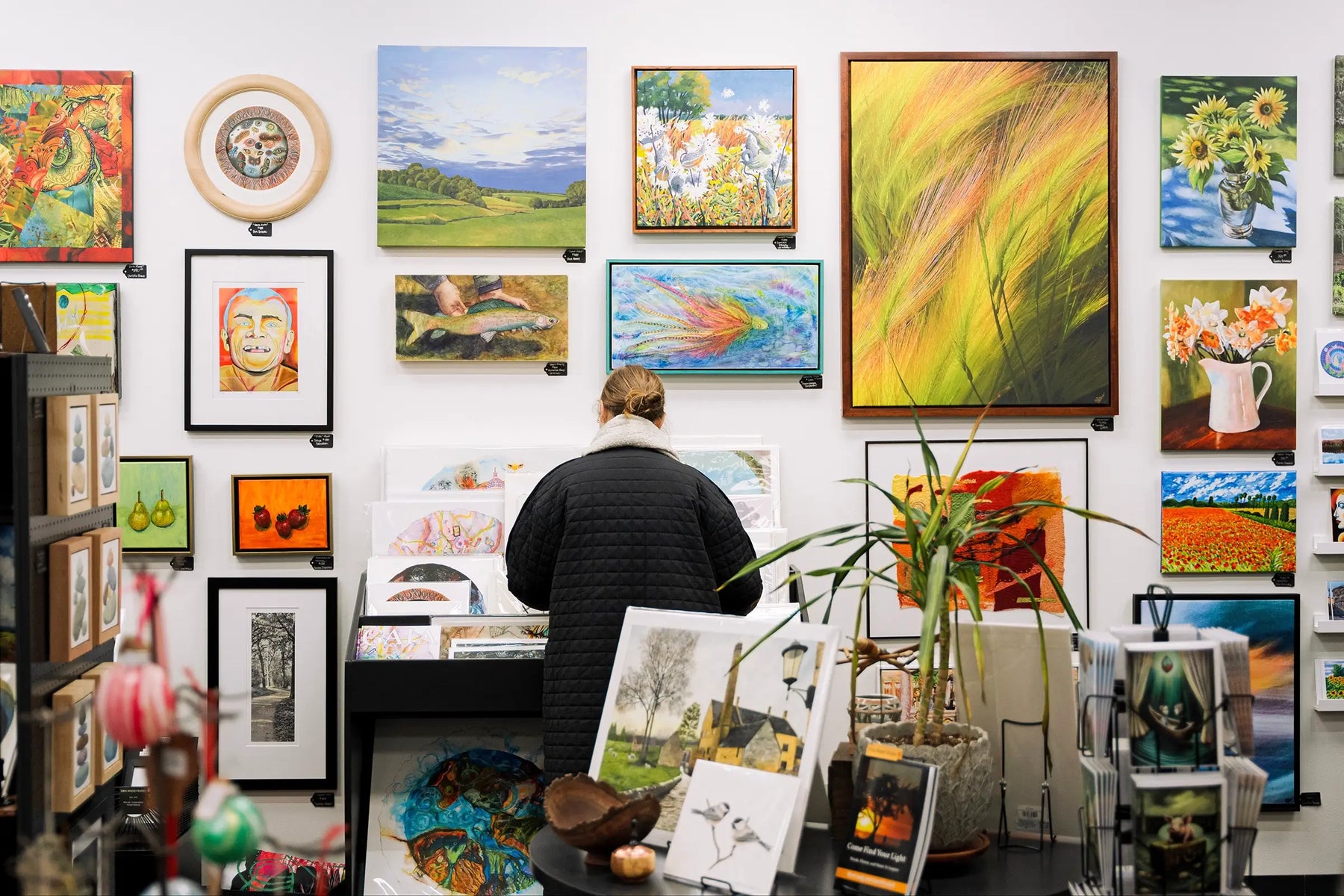 Customer browsing art prints and original artwork at Madison Art Market in Madison, Wisconsin.